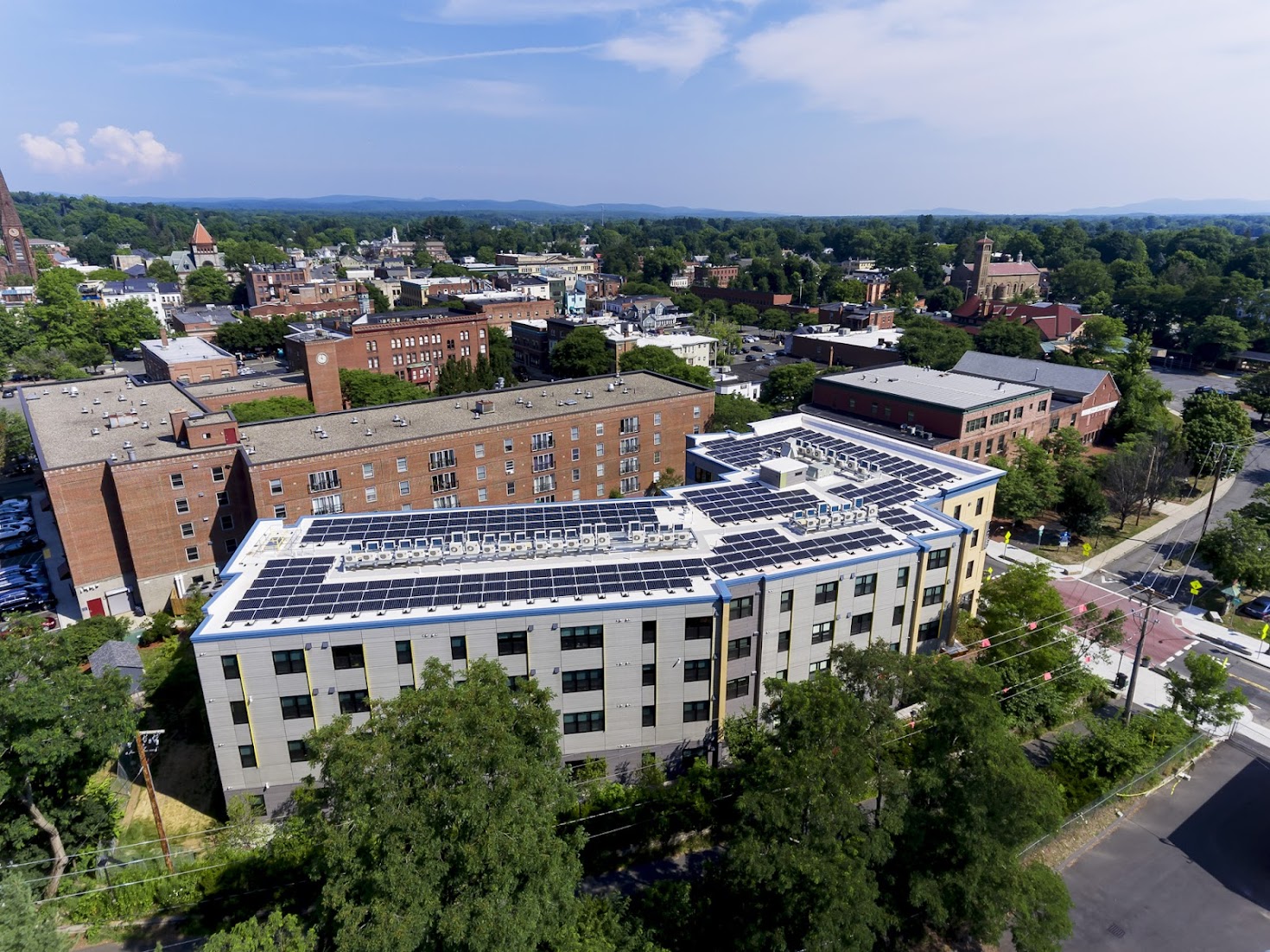 Aerial view of a large city building with rooftop solar panels.